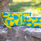 Image of yellow and blue Rivet Patterns Prelude Pouch sitting on rock